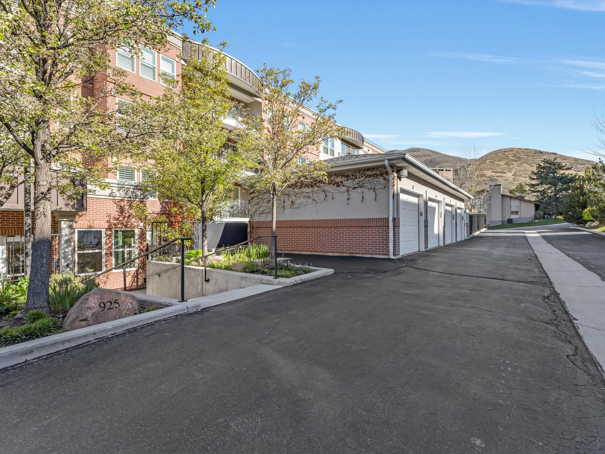 View of asphalt road featuring a mountain view and community garages