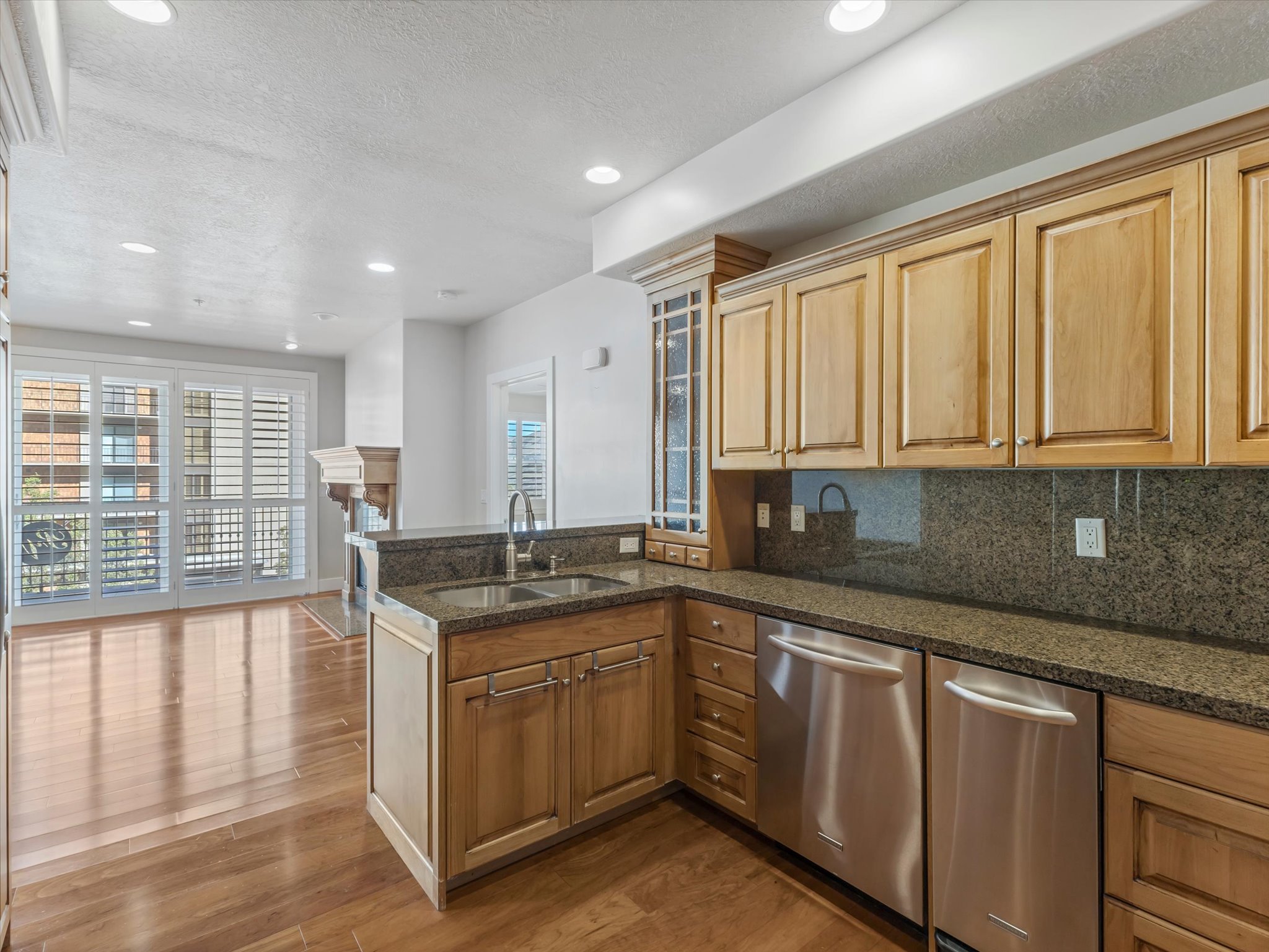 Kitchen with a peninsula, a textured ceiling, decorative backsplash, glass fronted cabinets, and dark wood finished floors