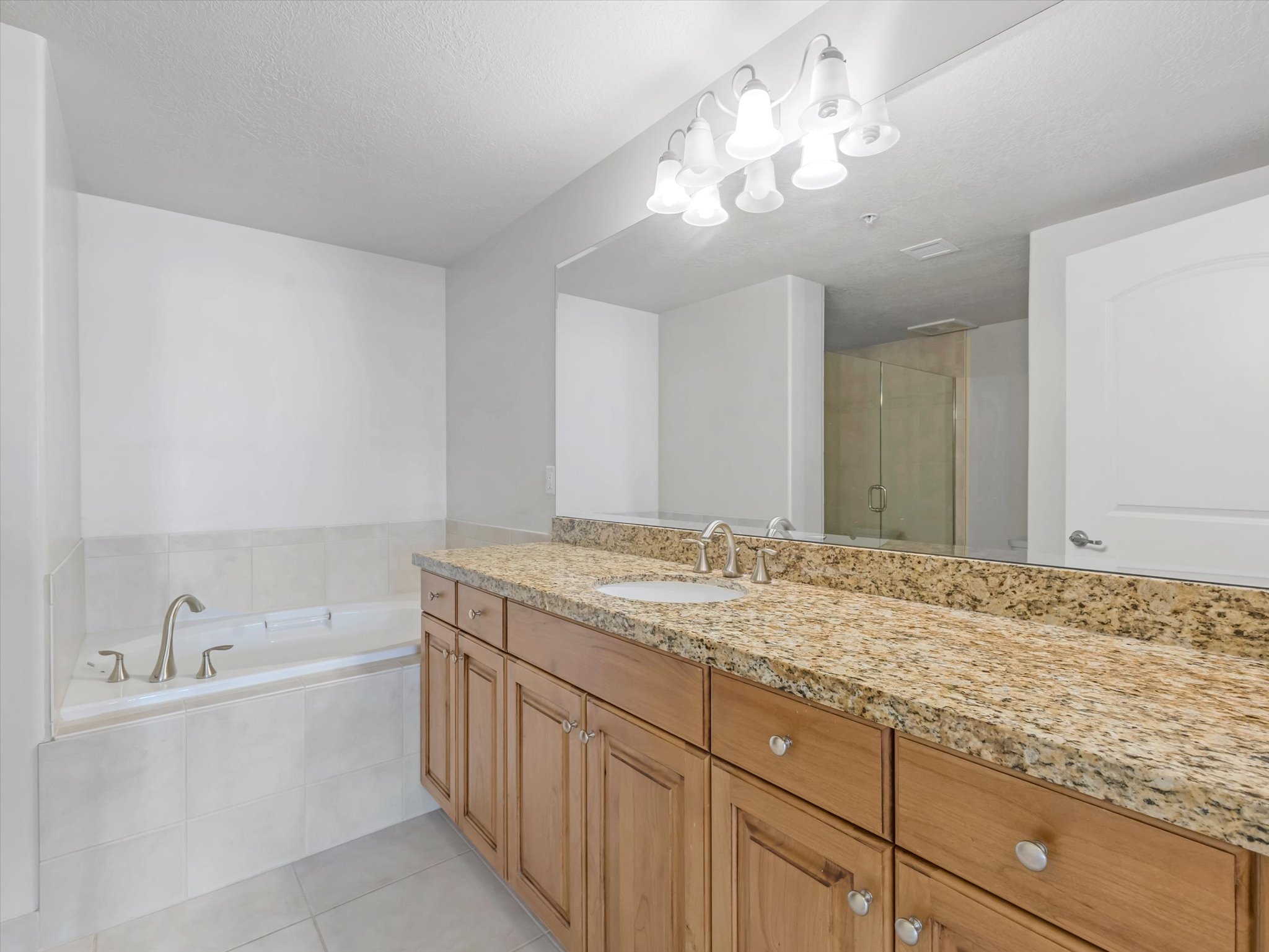 Bathroom featuring a bath, a shower stall, vanity, light tile patterned floors, and a textured ceiling