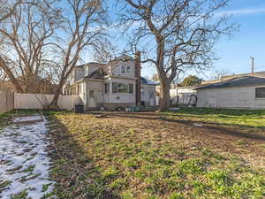 Back of house featuring a chimney, entry steps, and a fenced backyard