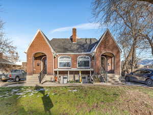 English style home featuring brick siding, a chimney, a front lawn, and roof with shingles