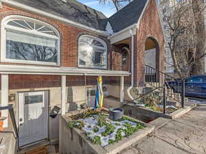 View of front facade with a shingled roof and brick siding