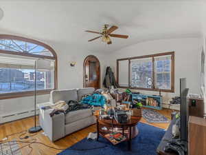 Living area featuring wood-type flooring, baseboard heating, ceiling fan, and vaulted ceiling