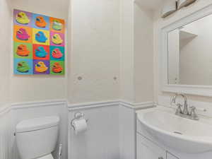 Bathroom featuring a wainscoted wall, a textured wall, vanity, and a decorative wall