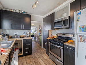 Kitchen with stainless steel appliances, ornamental molding, arched walkways, dark wood-style flooring, and backsplash