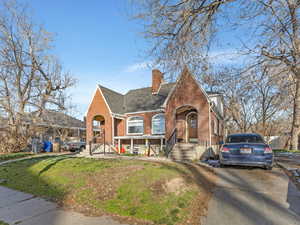 View of front of home featuring brick siding, a chimney, and a shingled roof