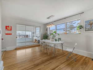 Dining area featuring light wood-style floors, plenty of natural light, and baseboard heating
