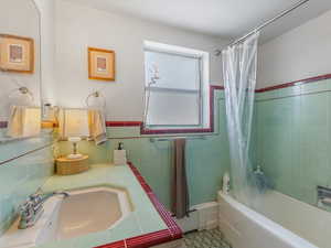 Bathroom with shower / bath combination with curtain and vanity