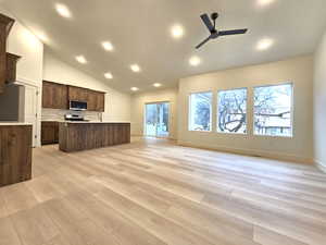Kitchen with stainless steel appliances, a center island with sink, open floor plan, lofted ceiling, and a ceiling fan