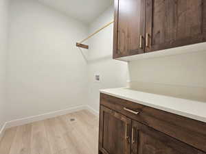 Laundry room with light wood-style flooring, hookup for a washing machine, and cabinet space