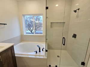 Full bath with vanity, a bath, and a stall shower