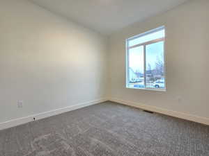 Empty room featuring baseboards and dark carpet