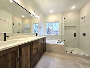 Bathroom featuring a shower stall, double vanity, a bath, and recessed lighting