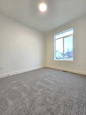 Spare room with dark colored carpet and baseboards