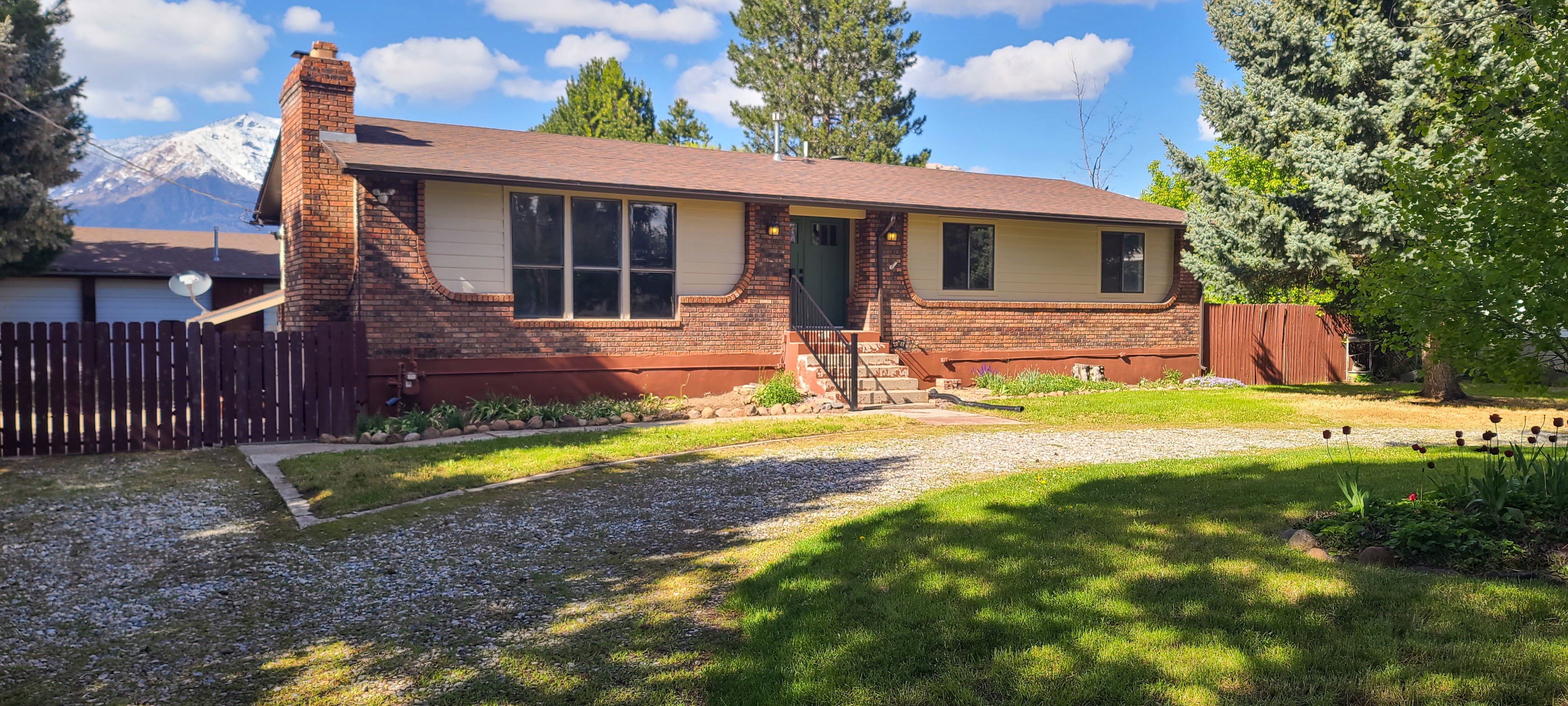 Brick and siding exterior with a brown roof and a rock driveway
