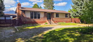 Brick and siding exterior with a brown roof and a rock driveway