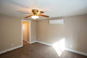 Carpeted master bedroom with a wall mounted mini split and a ceiling fan