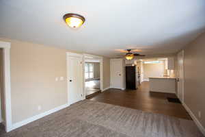 Unfurnished family room with a ceiling fan and dark LVP floors