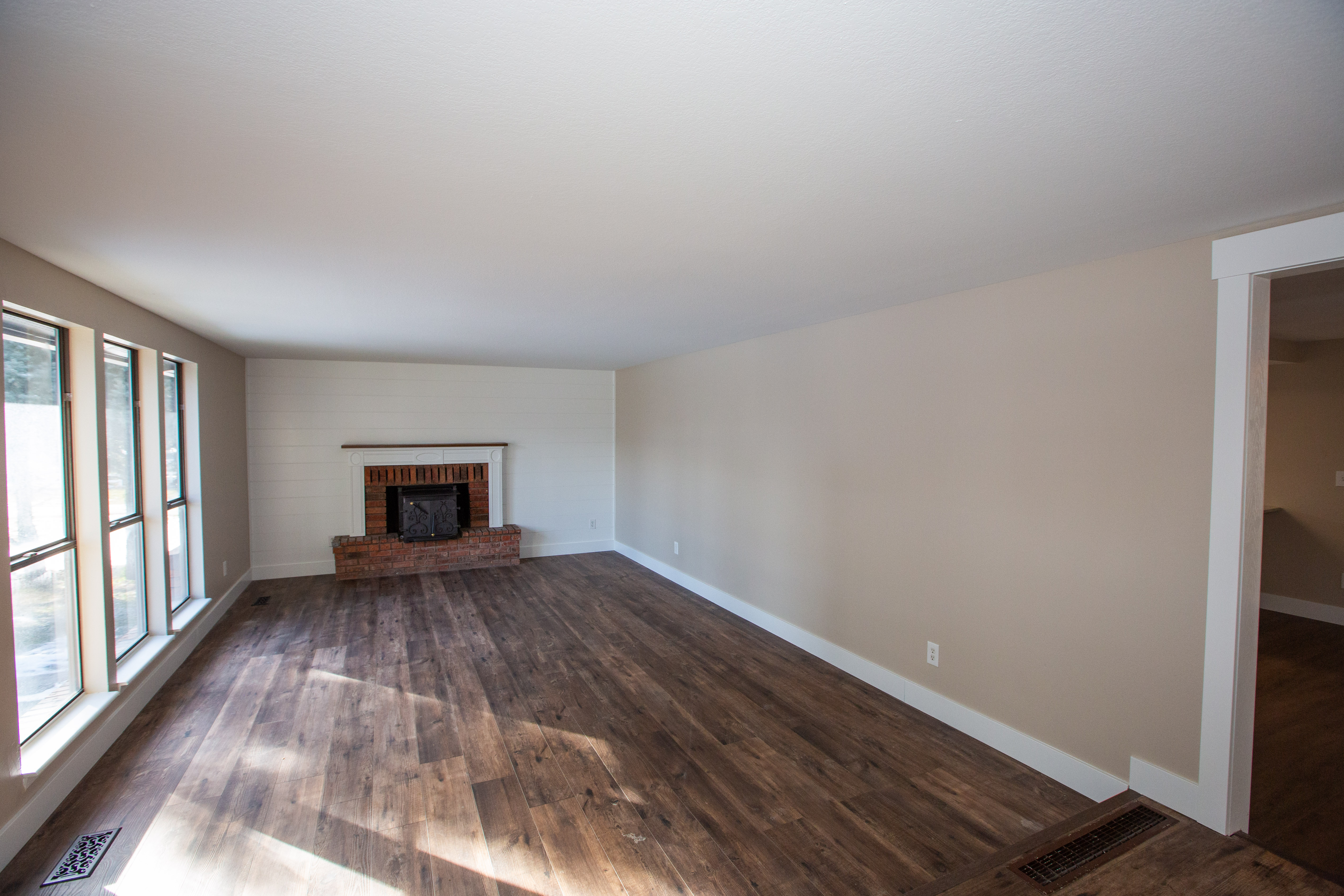 Lliving room with dark LVP floors and a brick fireplace