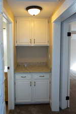 Hall cabinet and aounter featuring granite countertops, white cabinetry, and dark colored carpet