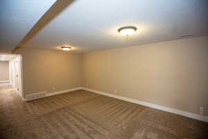Carpeted family room with a textured ceiling and baseboards