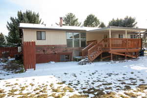 Rear view of property featuring brick siding and a covered wooden deck