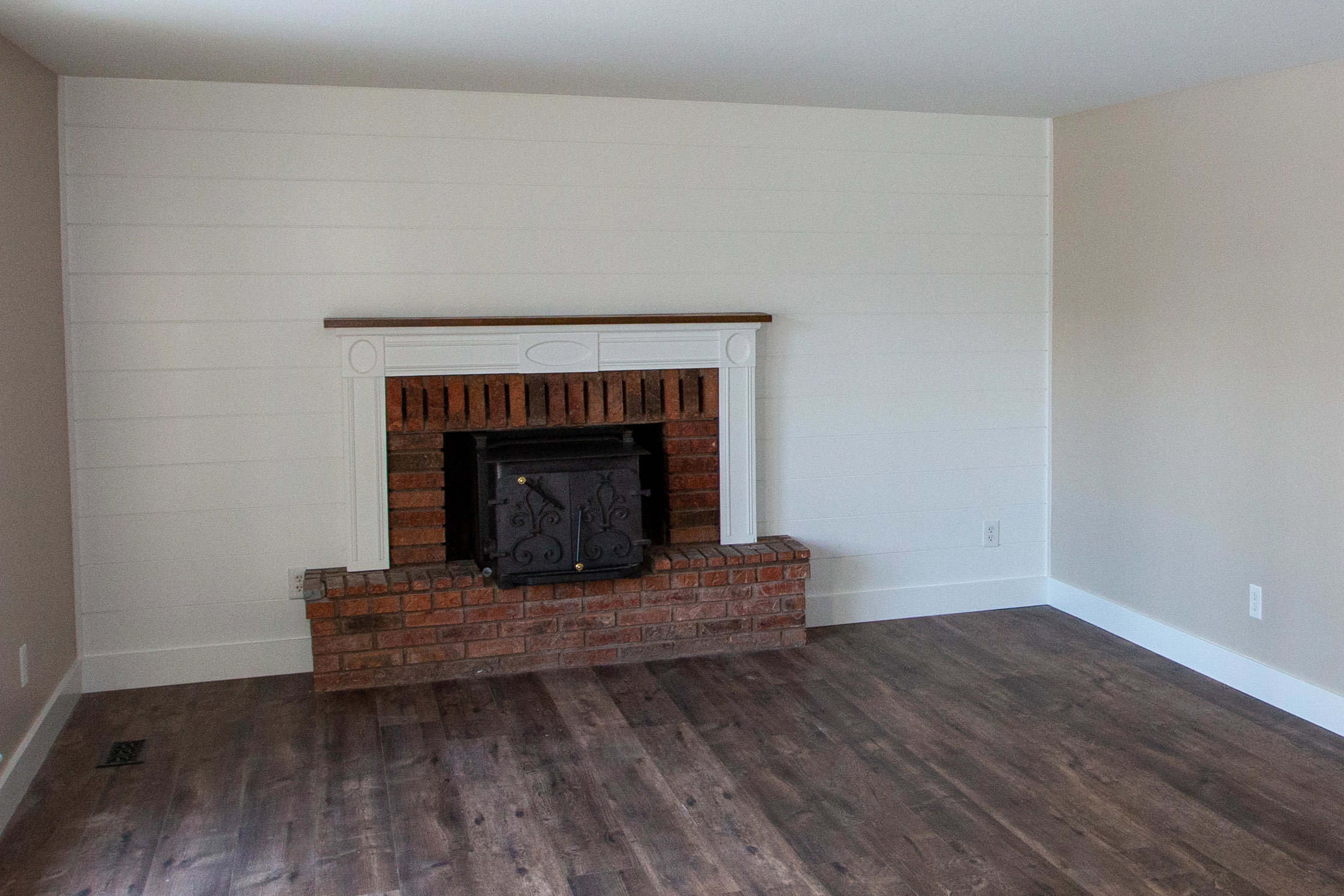 Unfurnished living room with darkLVP floors and a fireplace