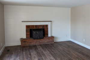 Unfurnished living room with darkLVP floors and a fireplace