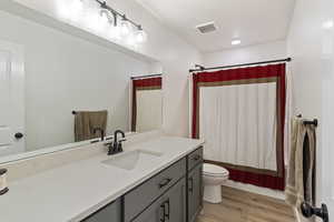 Bathroom with vanity, light wood finished floors, shower / tub combo with curtain, and recessed lighting