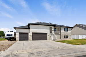 View of front of home with stone siding, a garage, concrete driveway, and a shingled roof
