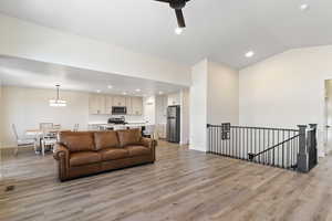 Living room featuring light wood-style floors, ceiling fan, recessed lighting, and lofted ceiling