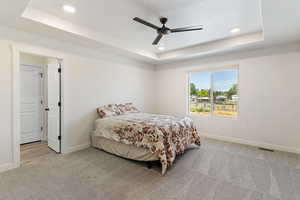 Bedroom featuring light colored carpet, ceiling fan, recessed lighting, and a tray ceiling