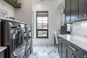 Laundry room featuring cabinet space, washer and clothes dryer, an office area, and light marble finish floors