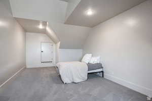 Carpeted bedroom with lofted ceiling and baseboards