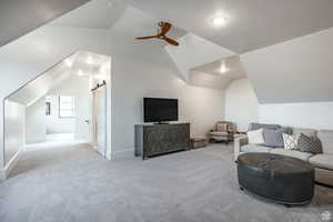 Sitting room with a barn door, a ceiling fan, and carpet flooring