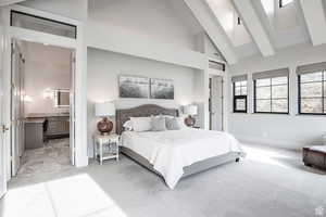 Carpeted bedroom featuring ensuite bath and vaulted ceiling
