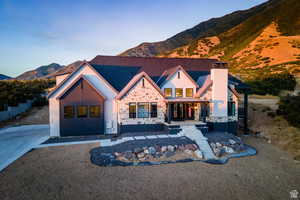 View of front facade with a mountain view, a porch, stone siding, and a chimney