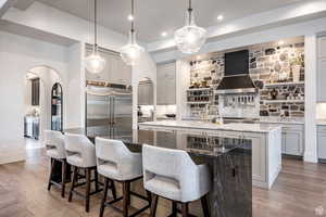Kitchen featuring dark stone countertops, arched walkways, a breakfast bar area, decorative light fixtures, and gray cabinets
