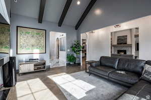 Living area with a premium fireplace, parquet floors, arched walkways, vaulted ceiling with beams, and recessed lighting