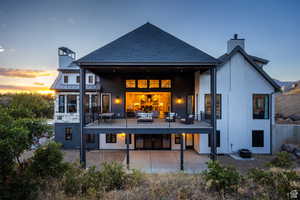 Back of property featuring a chimney, a patio area, roof with shingles, and stucco siding