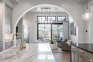Kitchen with dark stone countertops, gray cabinets, dark wood finished floors, arched walkways, and hanging lights