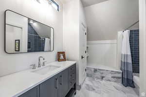 Full bath with vanity and lofted ceiling