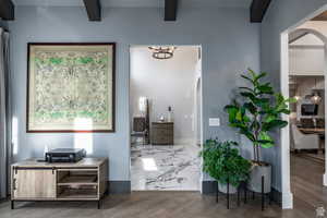 Hall featuring arched walkways, beam ceiling, and wood finished floors