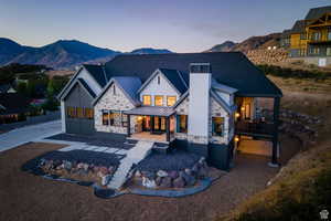 Back of house at dusk with stone siding, a standing seam roof, a mountain view, and a chimney