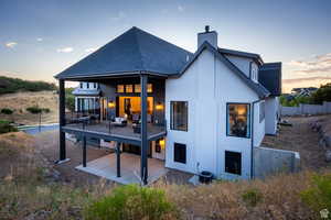 Rear view of property with a patio, roof with shingles, stucco siding, and a chimney