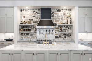 Kitchen featuring gray cabinetry, light stone countertops, and open shelves