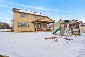 Snow covered house featuring a playground and stucco siding
