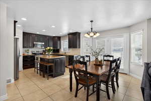 Dining area featuring hanging lights, light tile patterned floors, and a textured ceiling
