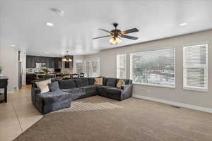 Living room with recessed lighting, light tile patterned floors, light colored carpet, and ceiling fan