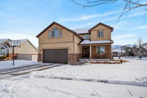Craftsman-style house featuring covered porch, an attached garage, stone siding, and driveway